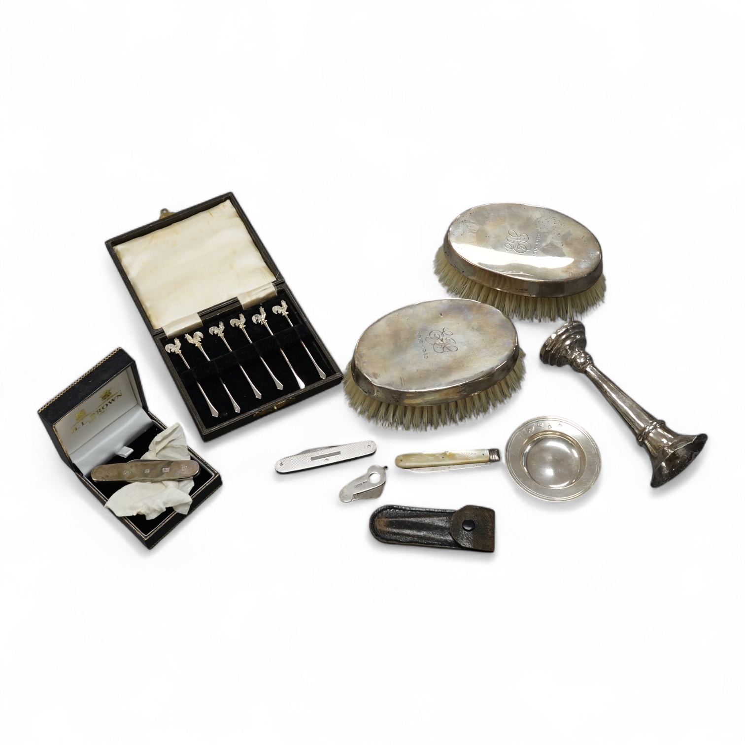 A small group of collectable silver including a pair of mounted clothes brushes, cased set of six cocktail sticks with cockerel terminals, mounted cigar cutter, pen knives, fruit knife etc. Condition - poor to fair